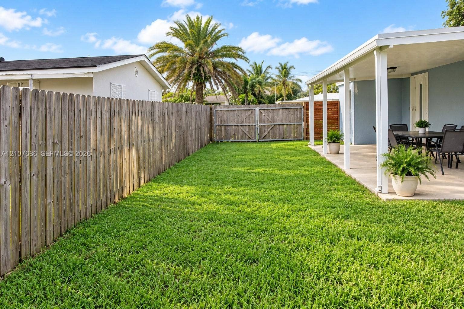 9760 Jamaica Drive, Cutler Bay, FL 33189 Fenced backyard featuring a manicured lawn, a covered concrete patio, and vertical wood privacy fencing