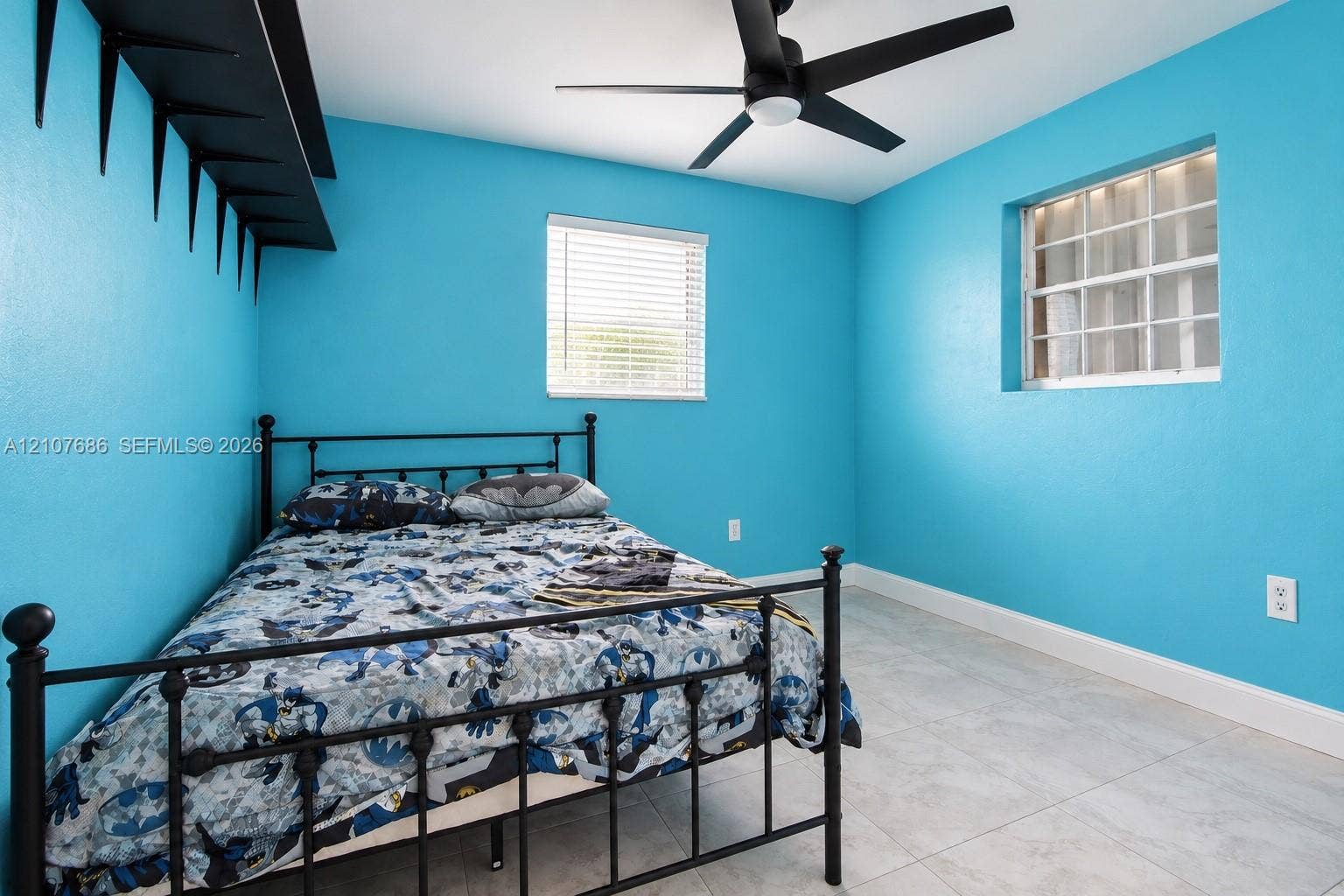 9760 Jamaica Drive, Cutler Bay, FL 33189 Neutral-toned tile flooring, matte black ceiling fan, dual windows with horizontal blinds, and a built-in wall-mounted shelf