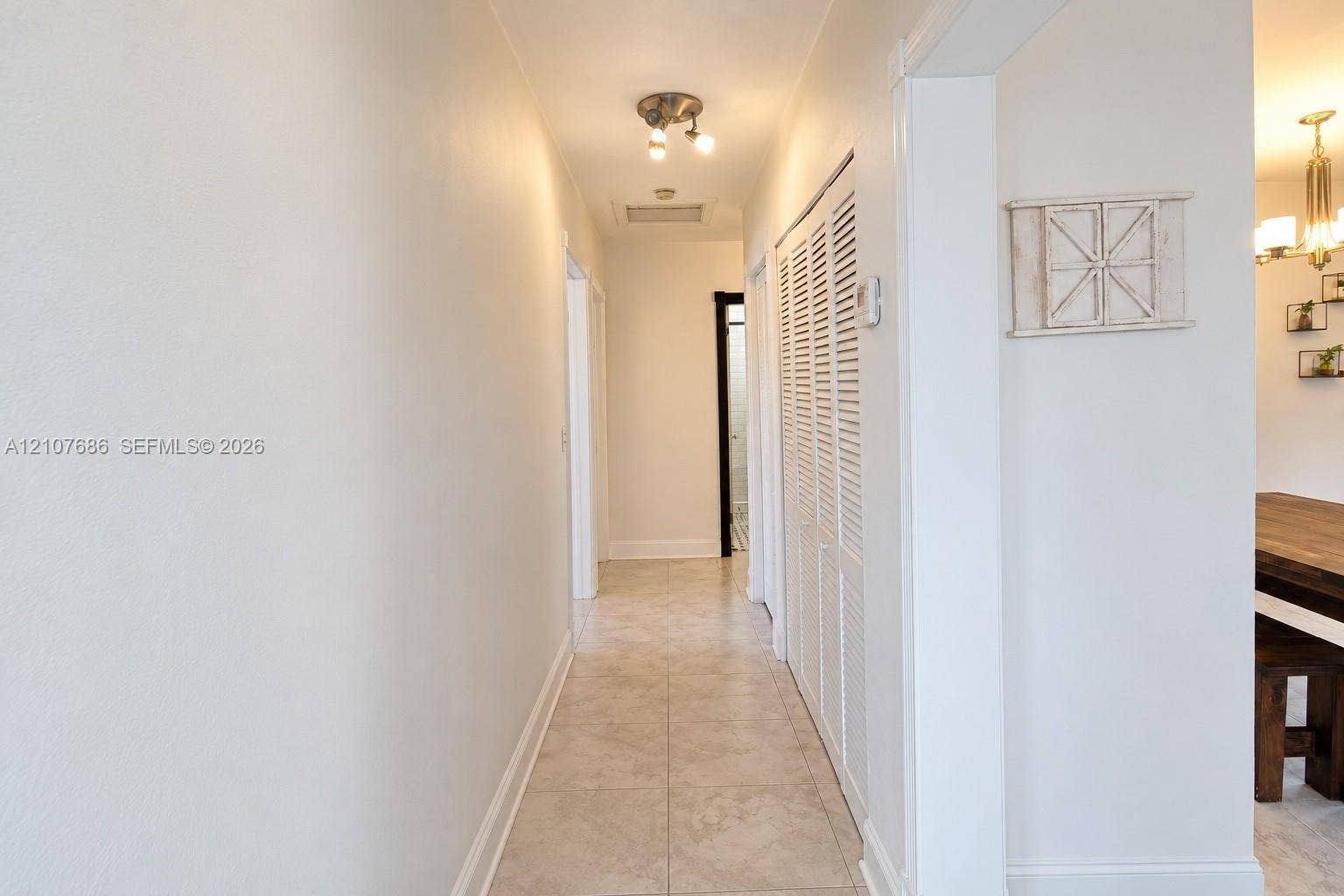 9760 Jamaica Drive, Cutler Bay, FL 33189 Hallway featuring neutral tile flooring, louvered closet doors, and a multi-bulb flush-mount ceiling fixture