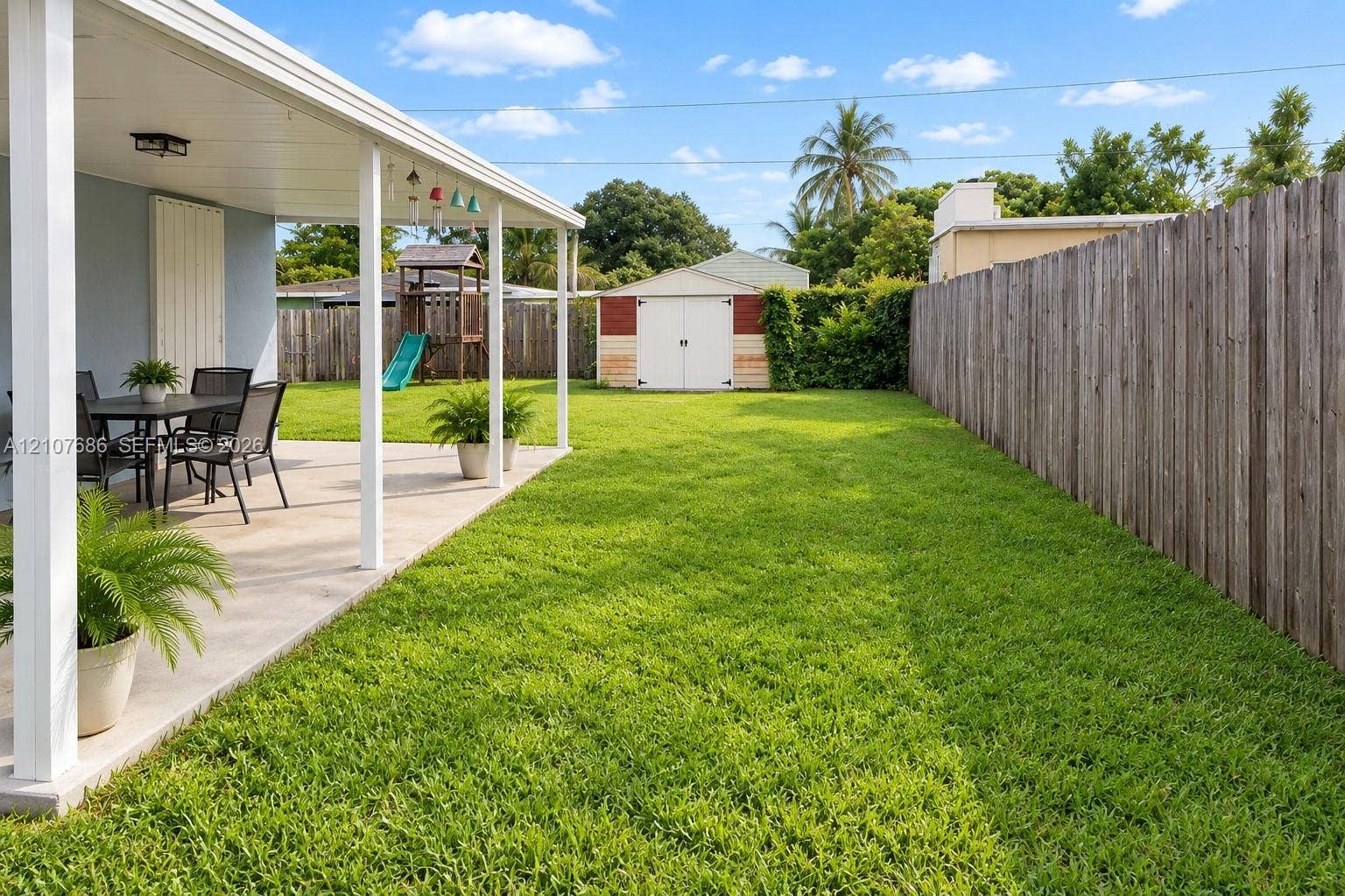 9760 Jamaica Drive, Cutler Bay, FL 33189 Covered concrete patio with white support columns, fenced backyard, and detached storage shed