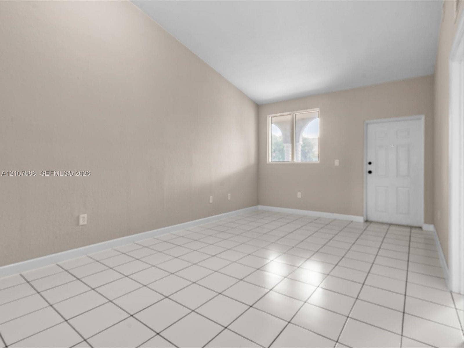 1677 SE 27th Court, #202, Homestead, FL 33035 Interior space featuring vaulted ceilings, light-toned ceramic tile flooring, neutral wall paint, and a white six-panel exterior entry door
