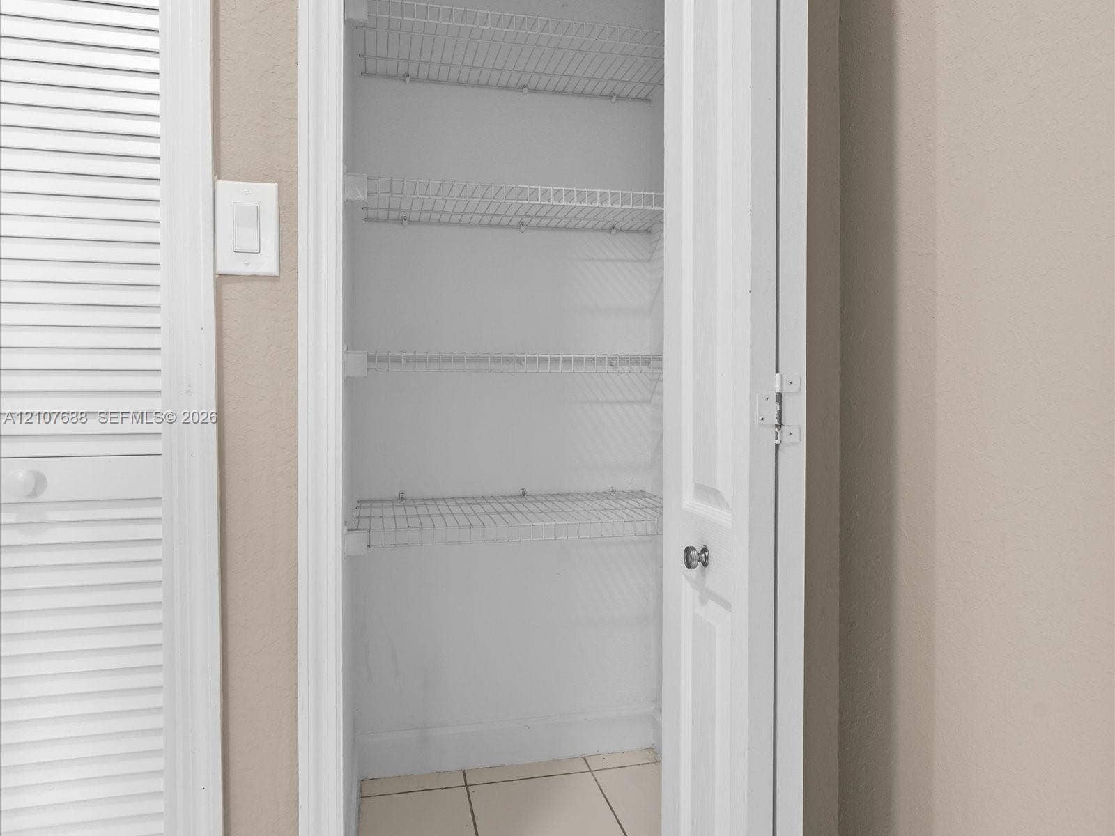 1677 SE 27th Court, #202, Homestead, FL 33035 Storage closet featuring white six-panel door, white wire shelving, and tile flooring