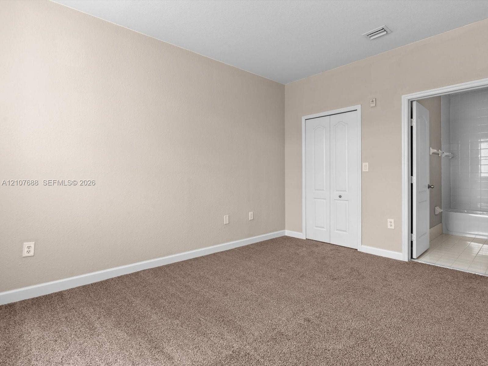 1677 SE 27th Court, #202, Homestead, FL 33035 Room featuring neutral wall tones, carpeted flooring, and a white bi-fold closet door