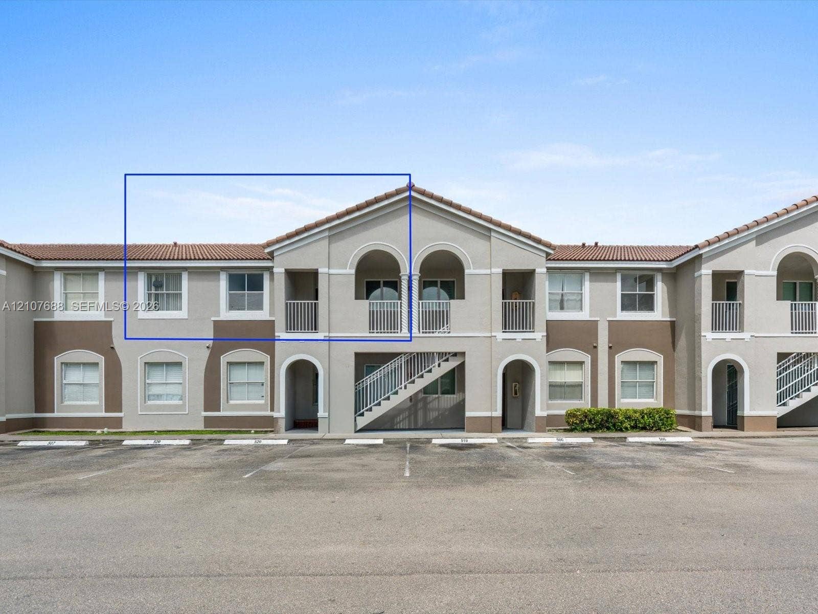 1677 SE 27th Court, #202, Homestead, FL 33035 Stucco exterior featuring arched architectural detailing, tile roof, private balcony, and multi-pane windows