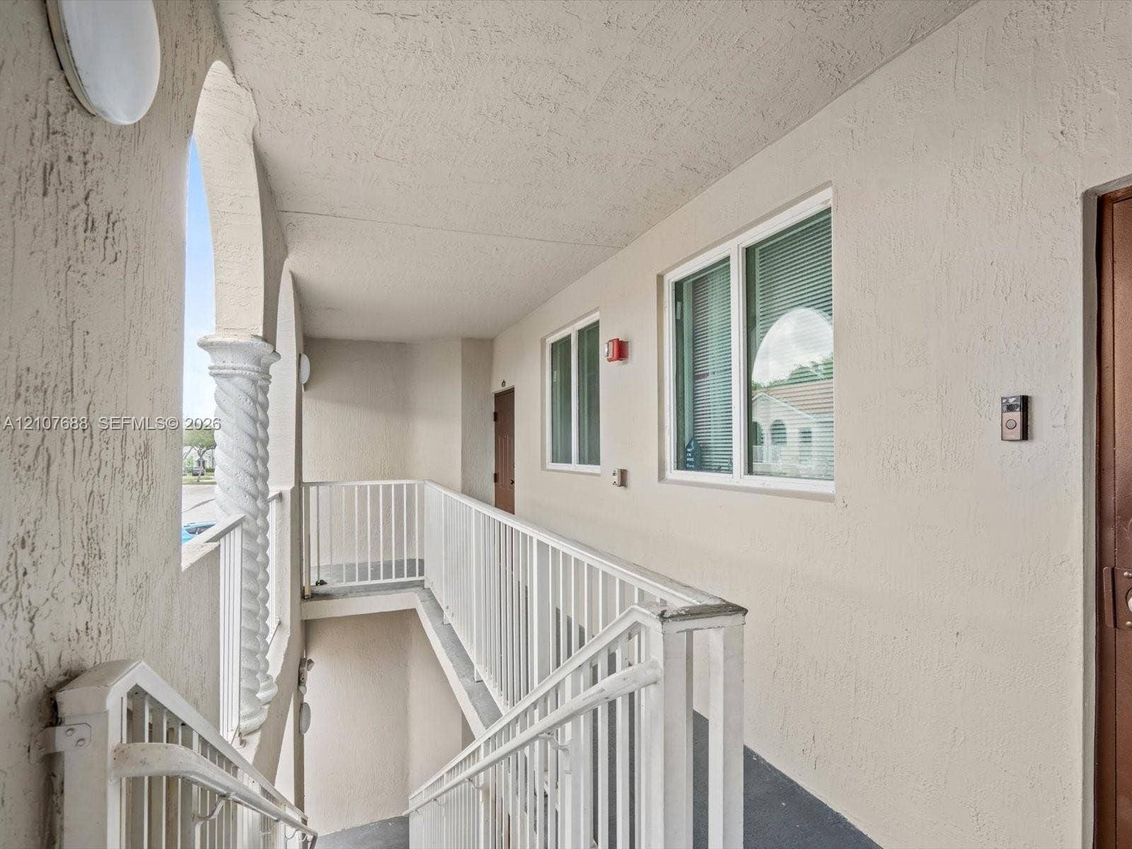 1677 SE 27th Court, #202, Homestead, FL 33035 Exterior walkway featuring stucco walls, a decorative spiral column, and white metal railings