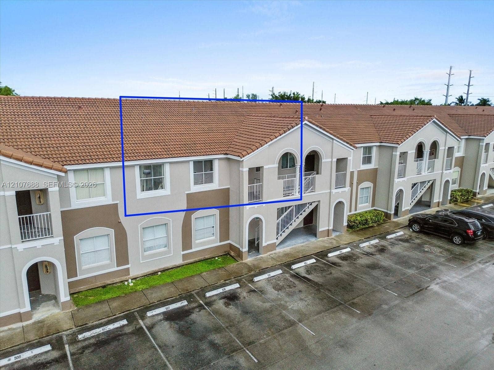 1677 SE 27th Court, #202, Homestead, FL 33035 Exterior elevation featuring terracotta-style roof tiles, light-toned stucco facade, arched window detailing, and balcony access
