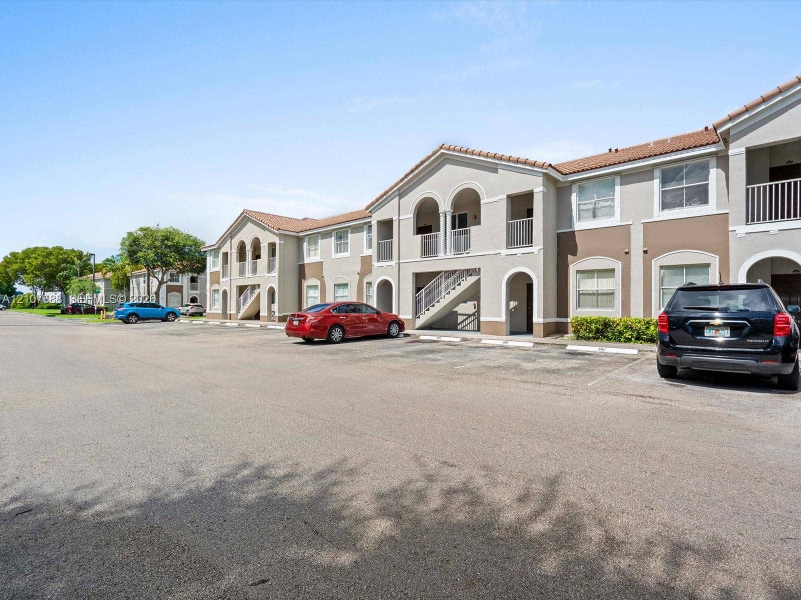 1677 SE 27th Court, #202, Homestead, FL 33035 Multi-story exterior featuring a stucco facade, arched architectural detailing, tile roofing, and private balconies with metal railings