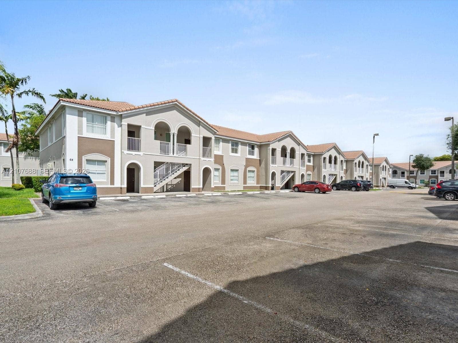 1677 SE 27th Court, #202, Homestead, FL 33035 Two-story building featuring stucco exterior, clay tile roof, arched entryway accents, and dedicated surface parking