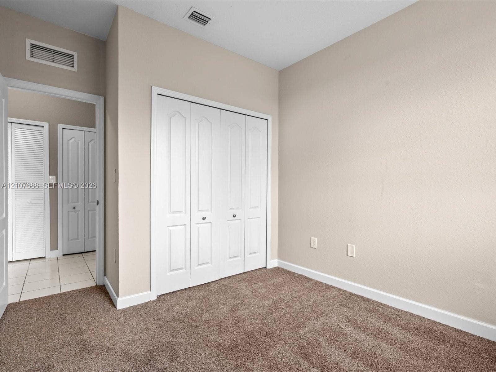 1677 SE 27th Court, #202, Homestead, FL 33035 Neutral wall tones, wall-to-wall carpeting, and four-panel bi-fold closet doors
