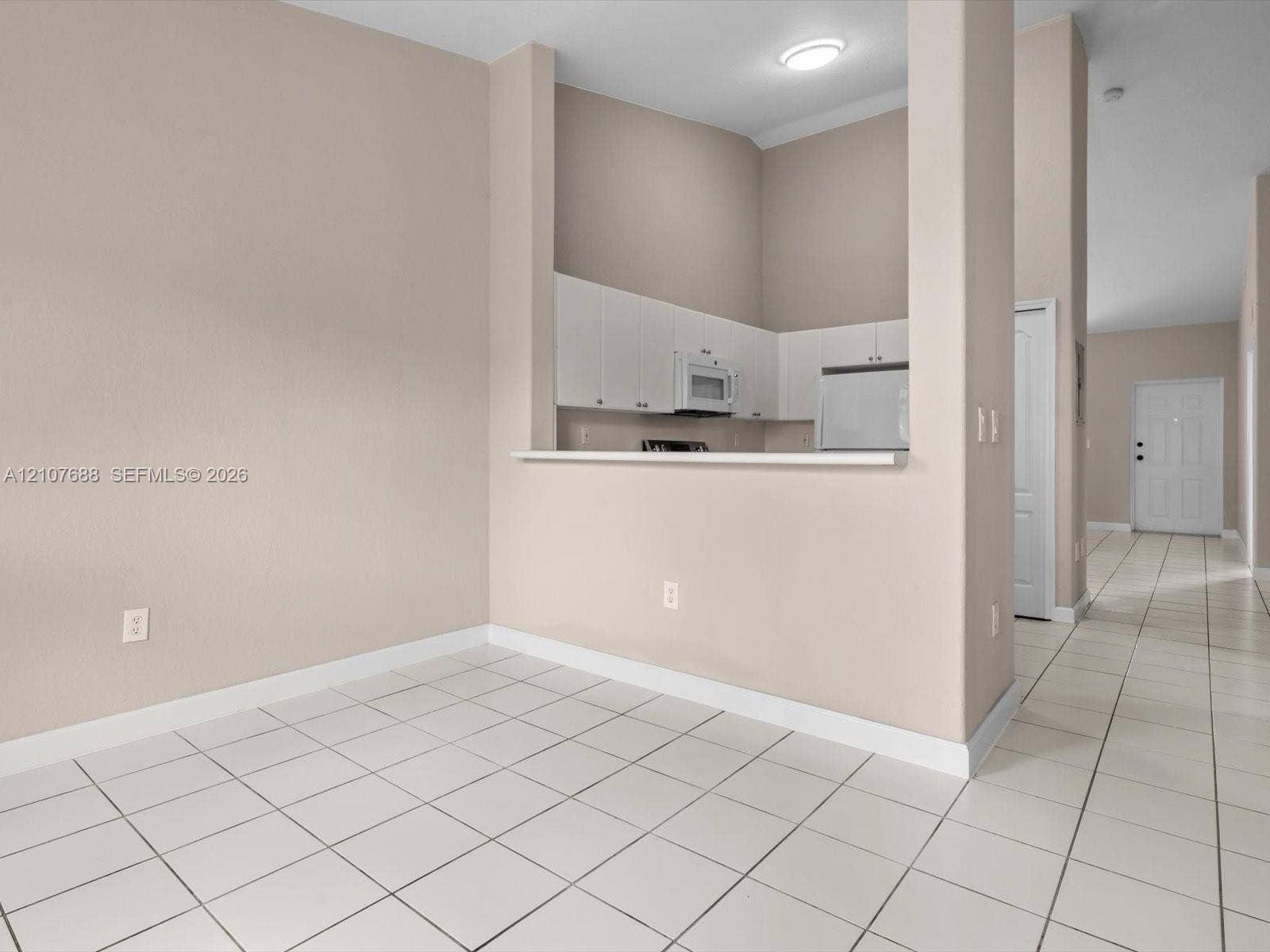 1677 SE 27th Court, #202, Homestead, FL 33035 Kitchen featuring white cabinetry, an integrated microwave, and a pass-through counter, with ceramic tile flooring throughout