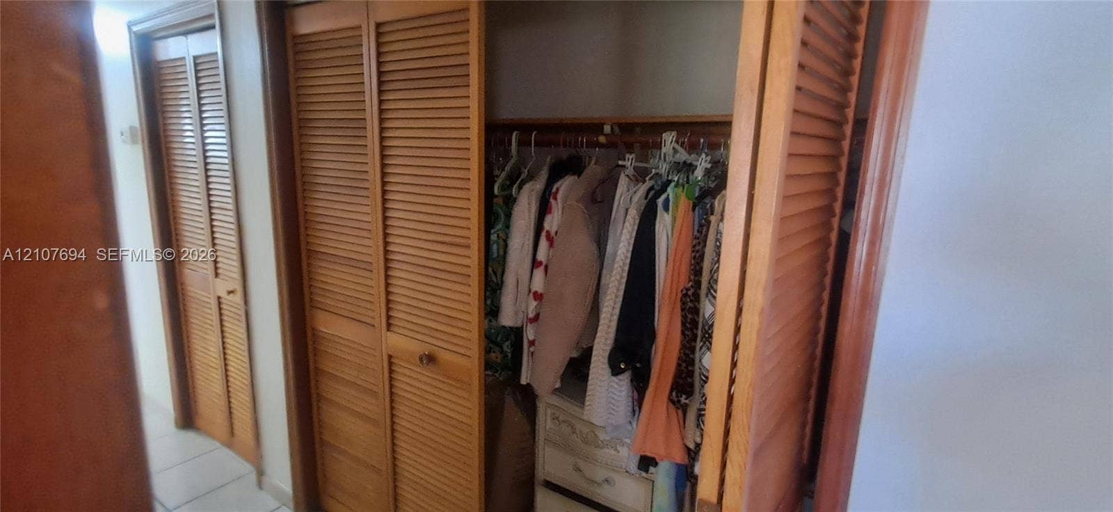 Storage area featuring wood louvered bifold doors and built-in wooden closet rod