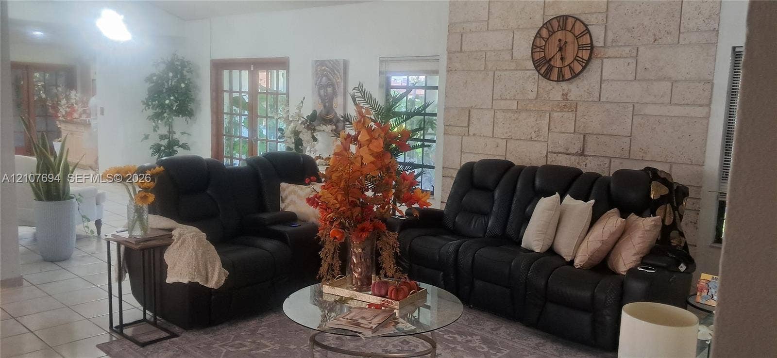 Living area featuring a floor-to-ceiling natural stone accent wall, light-toned ceramic tile flooring, and French doors