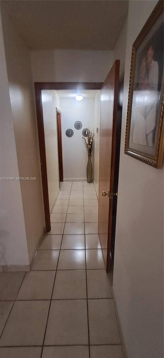 Hallway featuring large-format ceramic tile flooring, solid wood-finish door frames, and a flush-mount ceiling light fixture