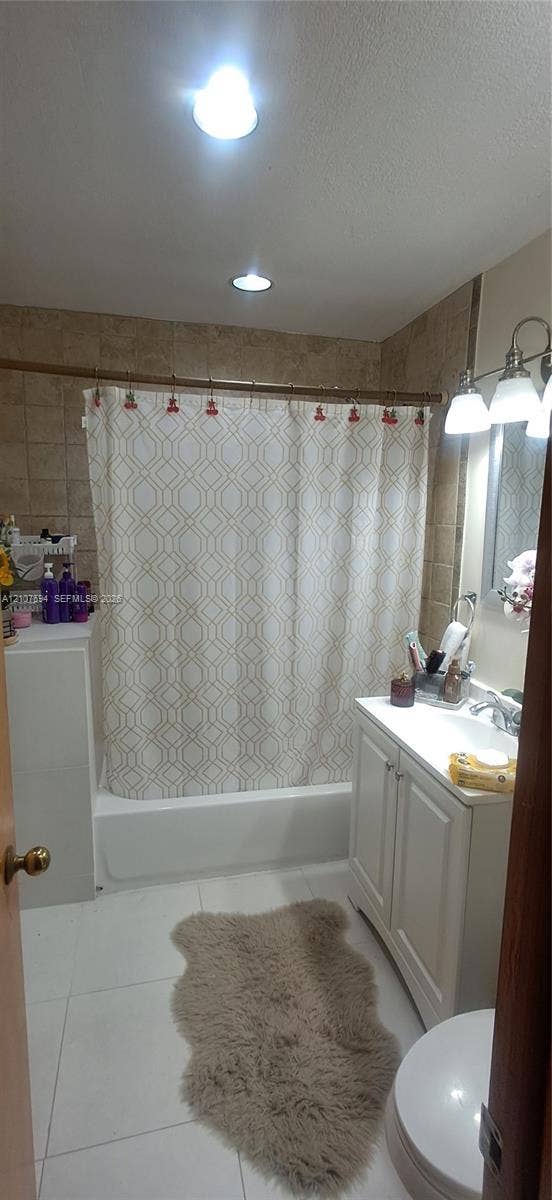 Bathroom featuring white cabinetry, tile wall surround, recessed lighting, and a three-bulb vanity fixture