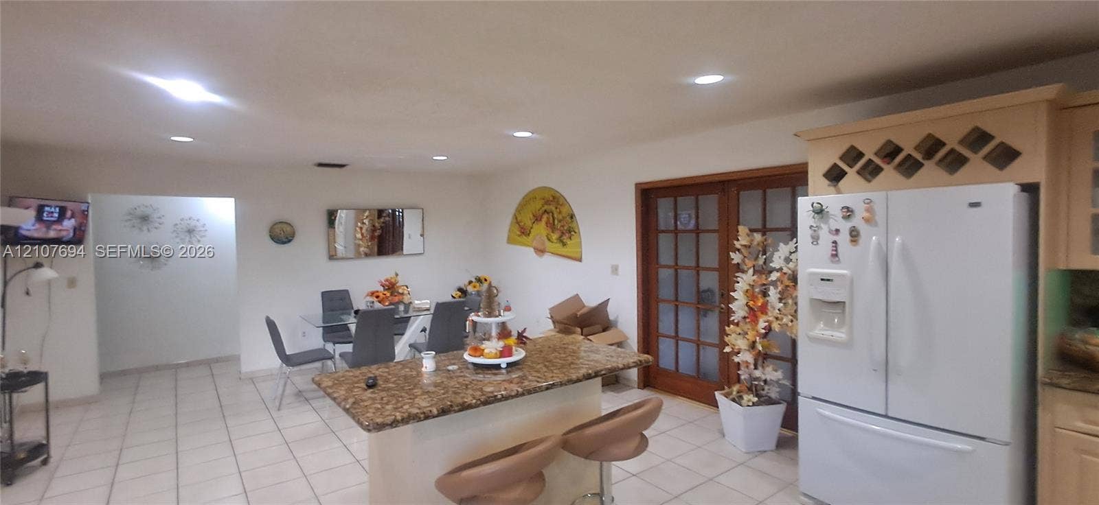 Kitchen featuring recessed lighting, a center island with a natural stone countertop, tile flooring, and glass-paneled double doors