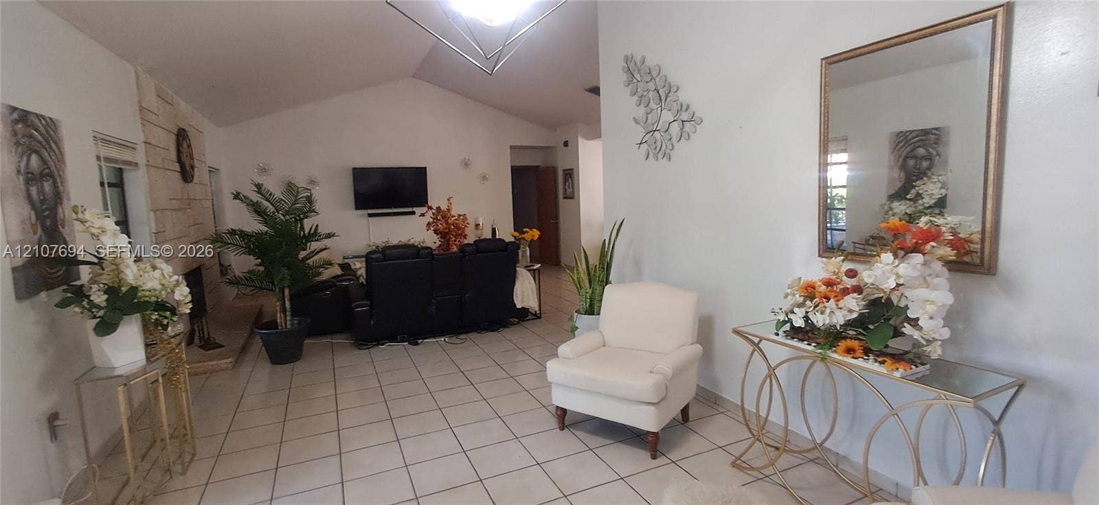 Living area featuring vaulted ceilings, light-toned ceramic tile flooring, and a floor-to-ceiling natural stone fireplace