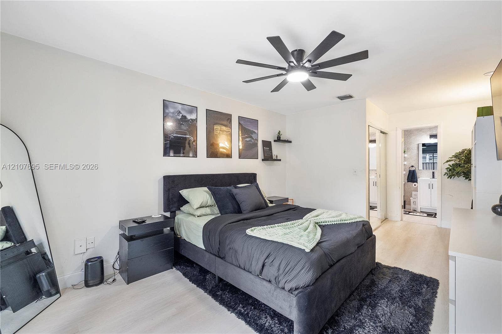 7198 Sportsmans Drive, North Lauderdale, FL 33068 Neutral-toned interior space featuring wood-finish flooring, a multi-blade ceiling fan with integrated lighting, and dual wall-mounted floating shelves