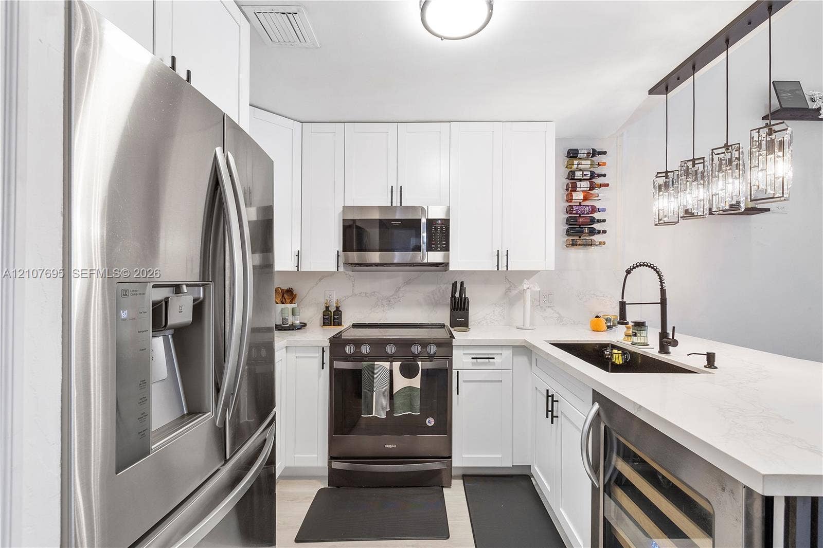 7198 Sportsmans Drive, North Lauderdale, FL 33068 Kitchen featuring white shaker-style cabinetry, white countertops with grey veining, stainless steel appliances, a black undermount sink with a gooseneck faucet, and multi-pendant overhead lighting