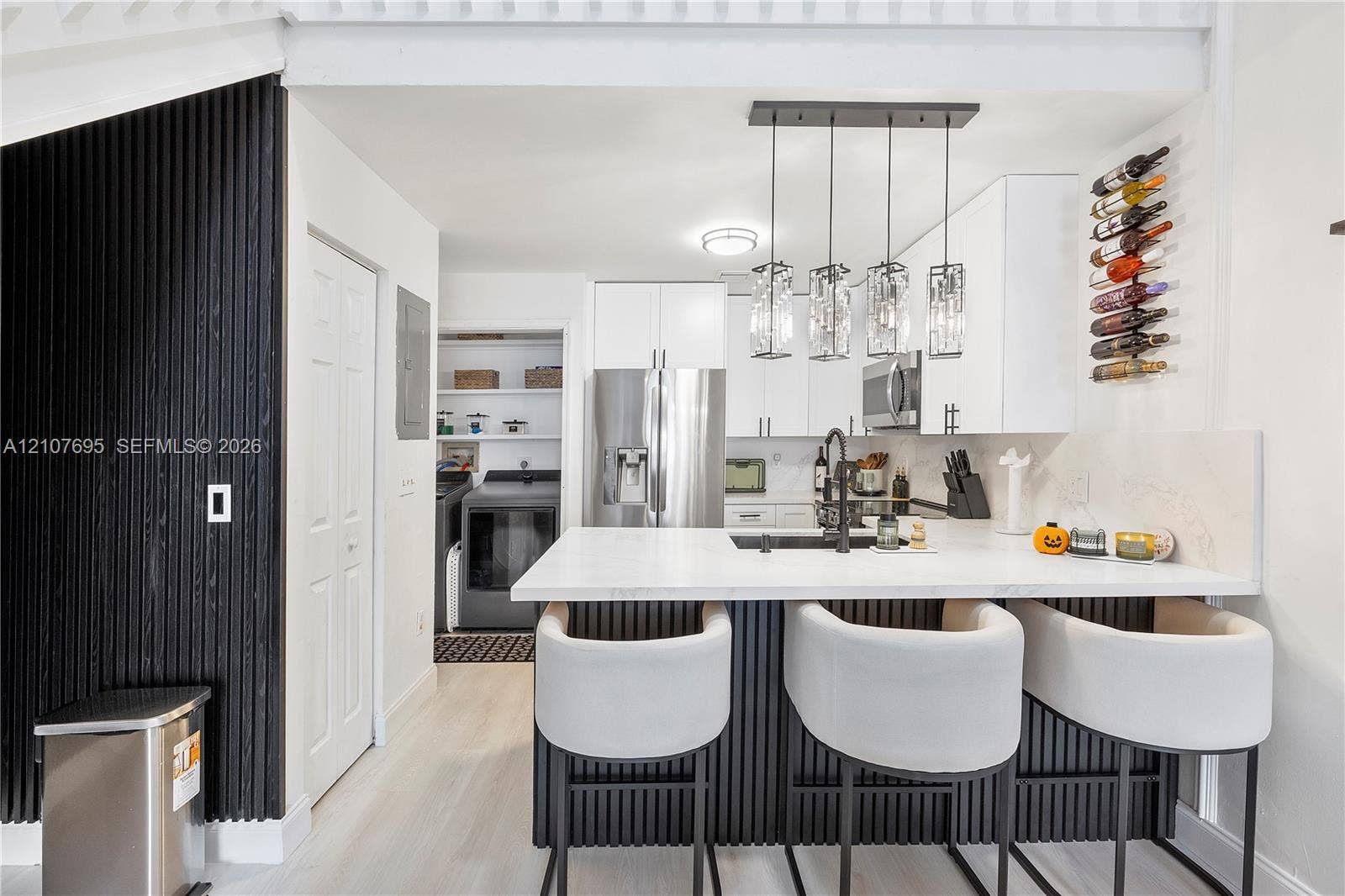 7198 Sportsmans Drive, North Lauderdale, FL 33068 Kitchen featuring white cabinetry, a quartz-topped island with vertical slat detailing, stainless steel appliances, a modern multi-pendant light fixture, and a built-in wall-mounted wine rack