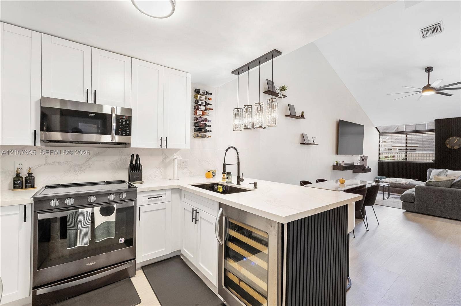 7198 Sportsmans Drive, North Lauderdale, FL 33068 Kitchen featuring white shaker-style cabinetry, quartz countertops with a matching backsplash, stainless steel appliances, a built-in wine refrigerator, and a matte black gooseneck faucet