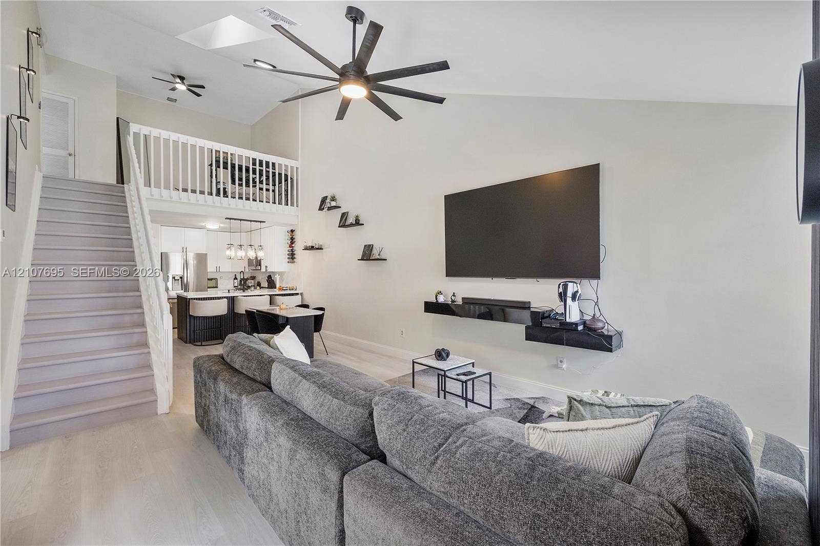 7198 Sportsmans Drive, North Lauderdale, FL 33068 Vaulted ceilings featuring a skylight, multi-blade ceiling fan, and vinyl staircase with white railings