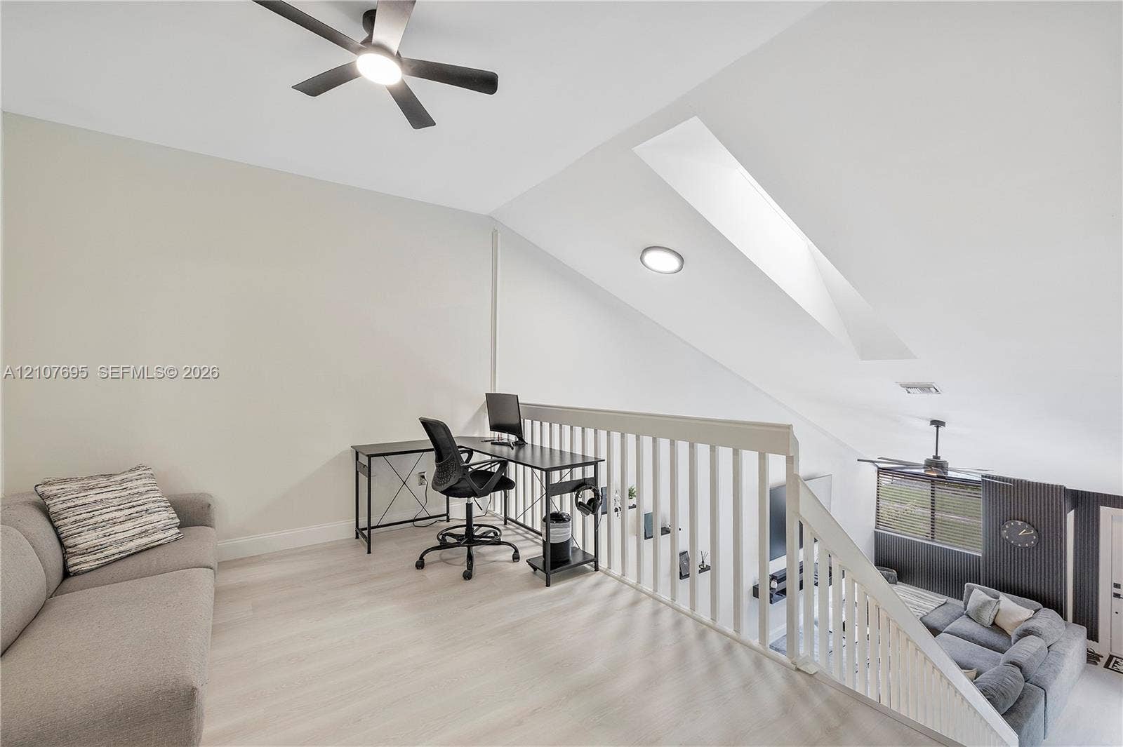 7198 Sportsmans Drive, North Lauderdale, FL 33068 Open loft area featuring vaulted ceilings, a skylight, wood-finish flooring, and a ceiling fan with integrated lighting