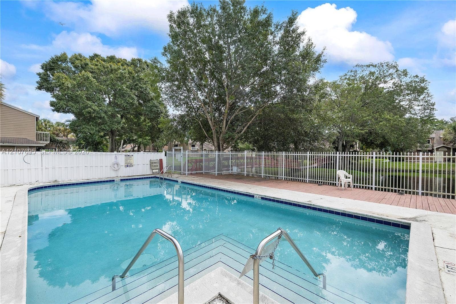 7198 Sportsmans Drive, North Lauderdale, FL 33068 Swimming pool featuring a concrete deck, metal railings, and a white privacy fence