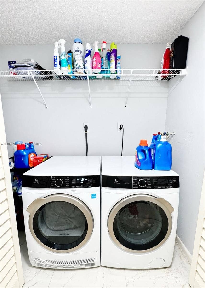 8290 Lake Drive, #418, Doral, FL 33166 Laundry area featuring white front-load appliances and wall-mounted wire shelving