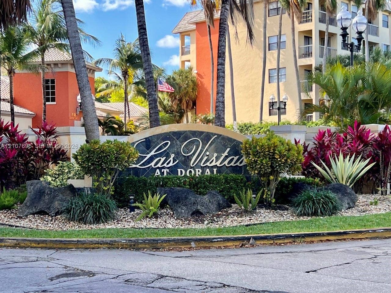 8290 Lake Drive, #418, Doral, FL 33166 Community entrance monument featuring a stone-inlay sign, mature palm trees, decorative rock accents, and established ornamental landscaping