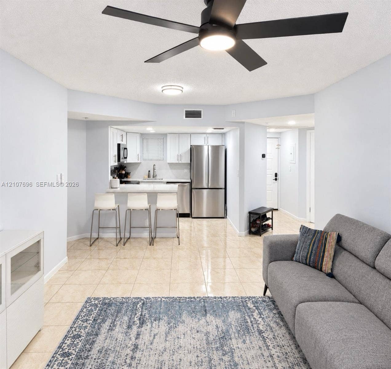 8290 Lake Drive, #418, Doral, FL 33166 Open-concept interior featuring light tile flooring, matte black ceiling fan with integrated lighting, stainless steel refrigerator, white cabinetry, and a peninsula counter