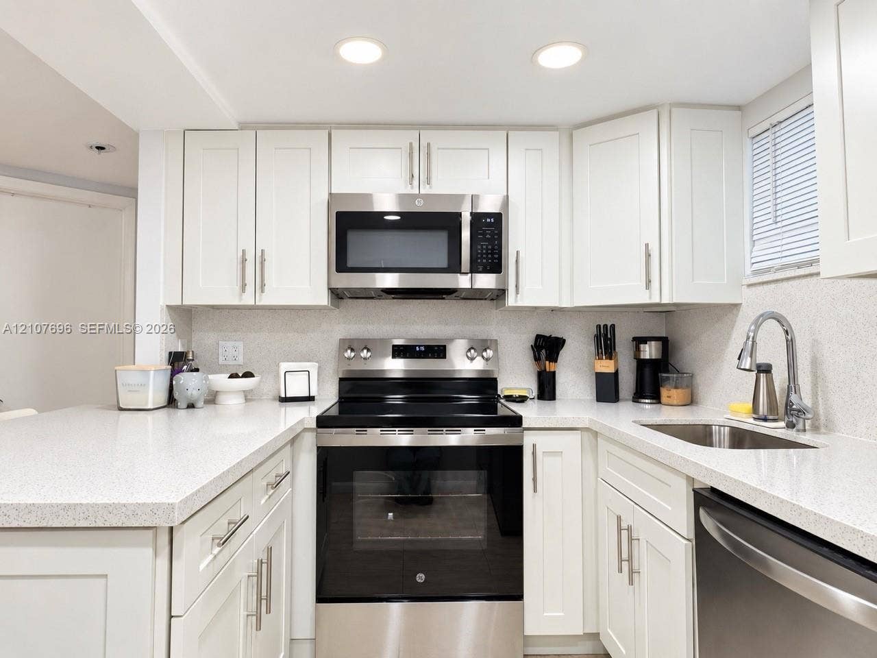8290 Lake Drive, #418, Doral, FL 33166 Kitchen featuring shaker-style cabinetry, solid-surface countertops, recessed lighting, and stainless-steel appliances including a range, microwave, and undermount sink
