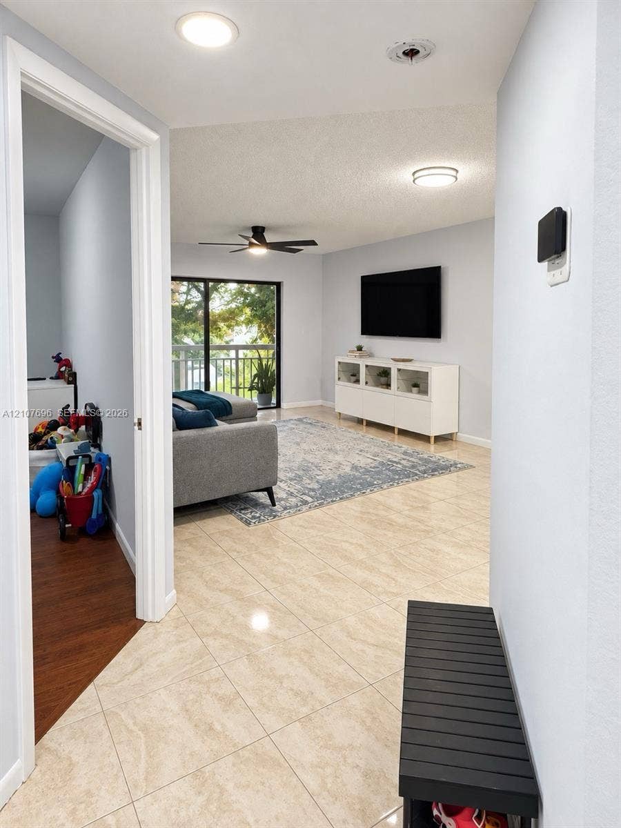 8290 Lake Drive, #418, Doral, FL 33166 Neutral-tone large-format tile flooring, recessed overhead lighting, matte black ceiling fan, and sliding glass doors with balcony access
