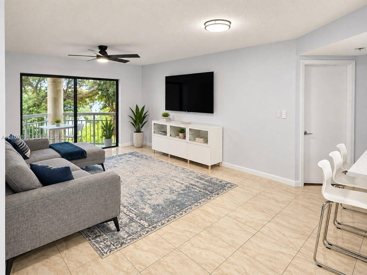 8290 Lake Drive, #418, Doral, FL 33166 Living area featuring neutral tile flooring, a matte black ceiling fan, and a large sliding glass door providing natural light