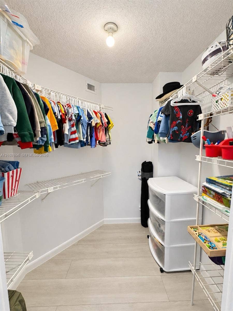 8290 Lake Drive, #418, Doral, FL 33166 Walk-in closet featuring light-toned wood-finish flooring and multiple levels of integrated wire shelving