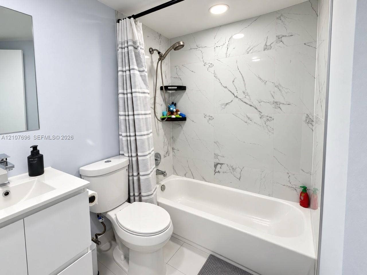 8290 Lake Drive, #418, Doral, FL 33166 Bathroom featuring white vanity with integrated sink, porcelain tile surround with veined finish, chrome handheld shower fixture, and recessed lighting