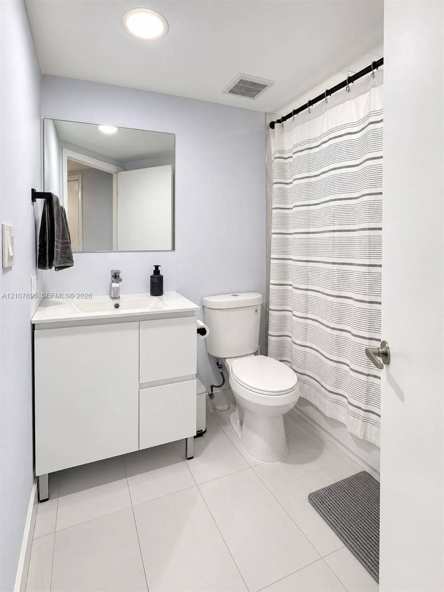 8290 Lake Drive, #418, Doral, FL 33166 Modern white vanity with a rectangular sink, frameless wall-mounted mirror, polished chrome faucet, and large-format tile flooring