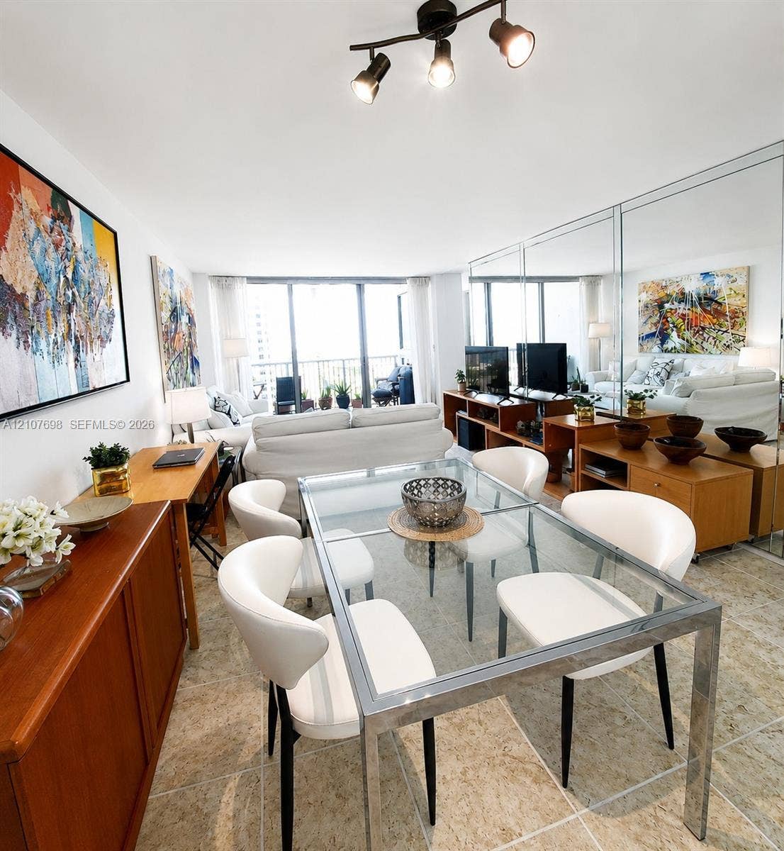 Open-concept living space featuring floor-to-ceiling mirrored walls, large-format stone-finish tile flooring, and multi-light track lighting