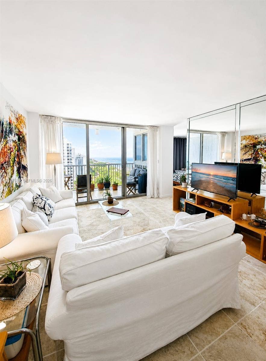 Living area featuring floor-to-ceiling glass sliding doors, stone tile flooring, and a mirrored wall accent