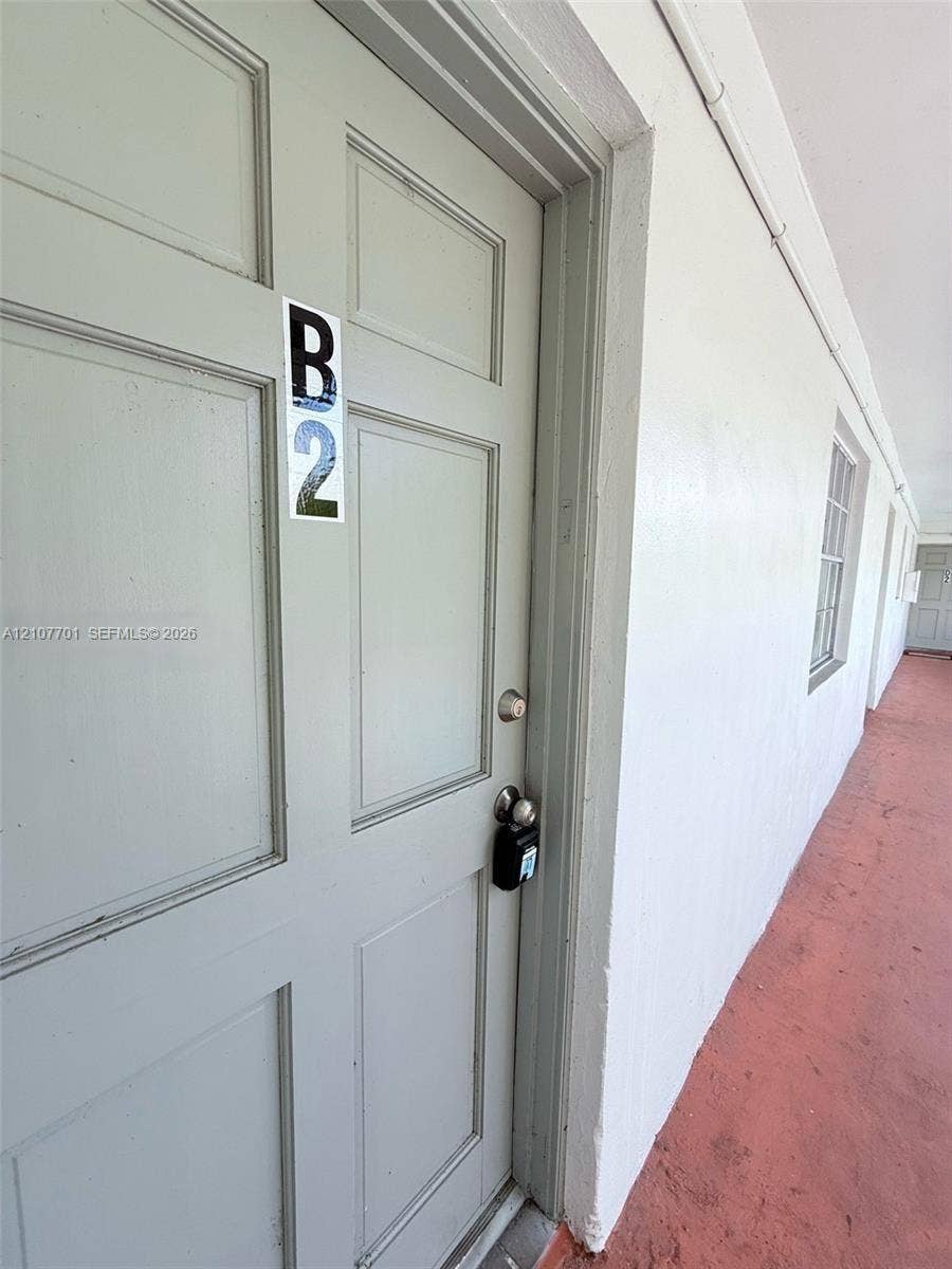 3100 Coral Springs Drive, #2B, Coral Springs, FL 33065 Six-panel exterior door with a satin-finish cylindrical lockset and metallic numerical unit identifier