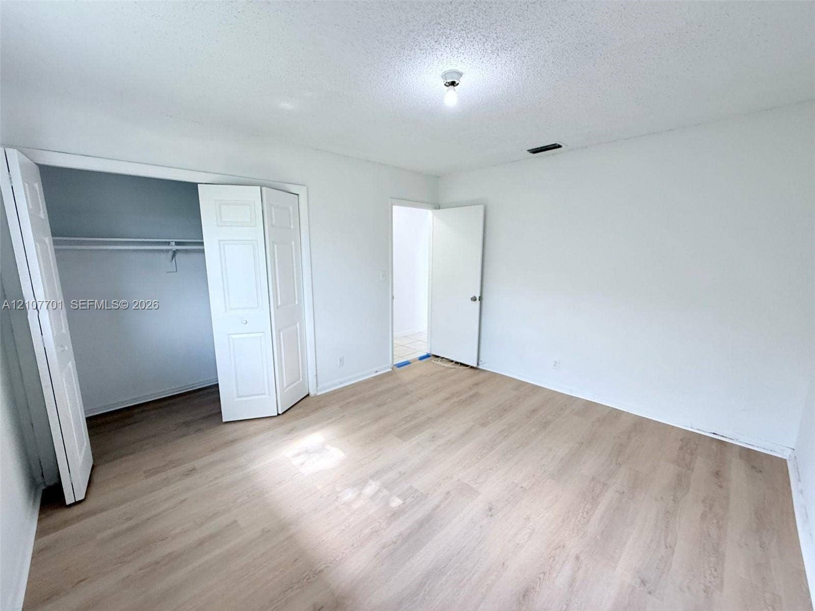 3100 Coral Springs Drive, #2B, Coral Springs, FL 33065 Interior space featuring wood-finish flooring, a built-in reach-in closet with double-panel doors, and a standard swinging door entry