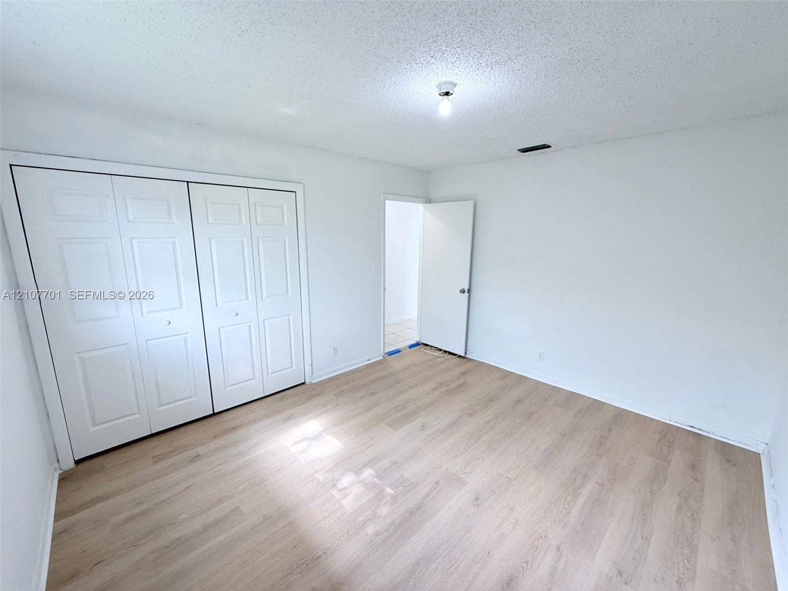 3100 Coral Springs Drive, #2B, Coral Springs, FL 33065 Room featuring wood-finish flooring, dual-panel closet doors, and a ceiling-mounted light fixture
