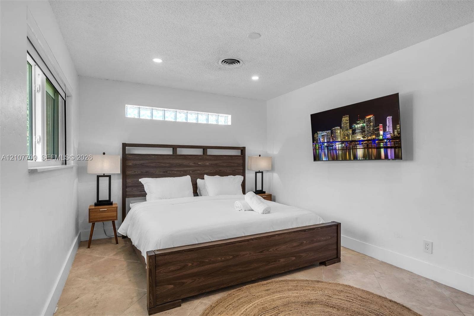 Room featuring light-toned tile flooring, recessed lighting, and a horizontal glass block window