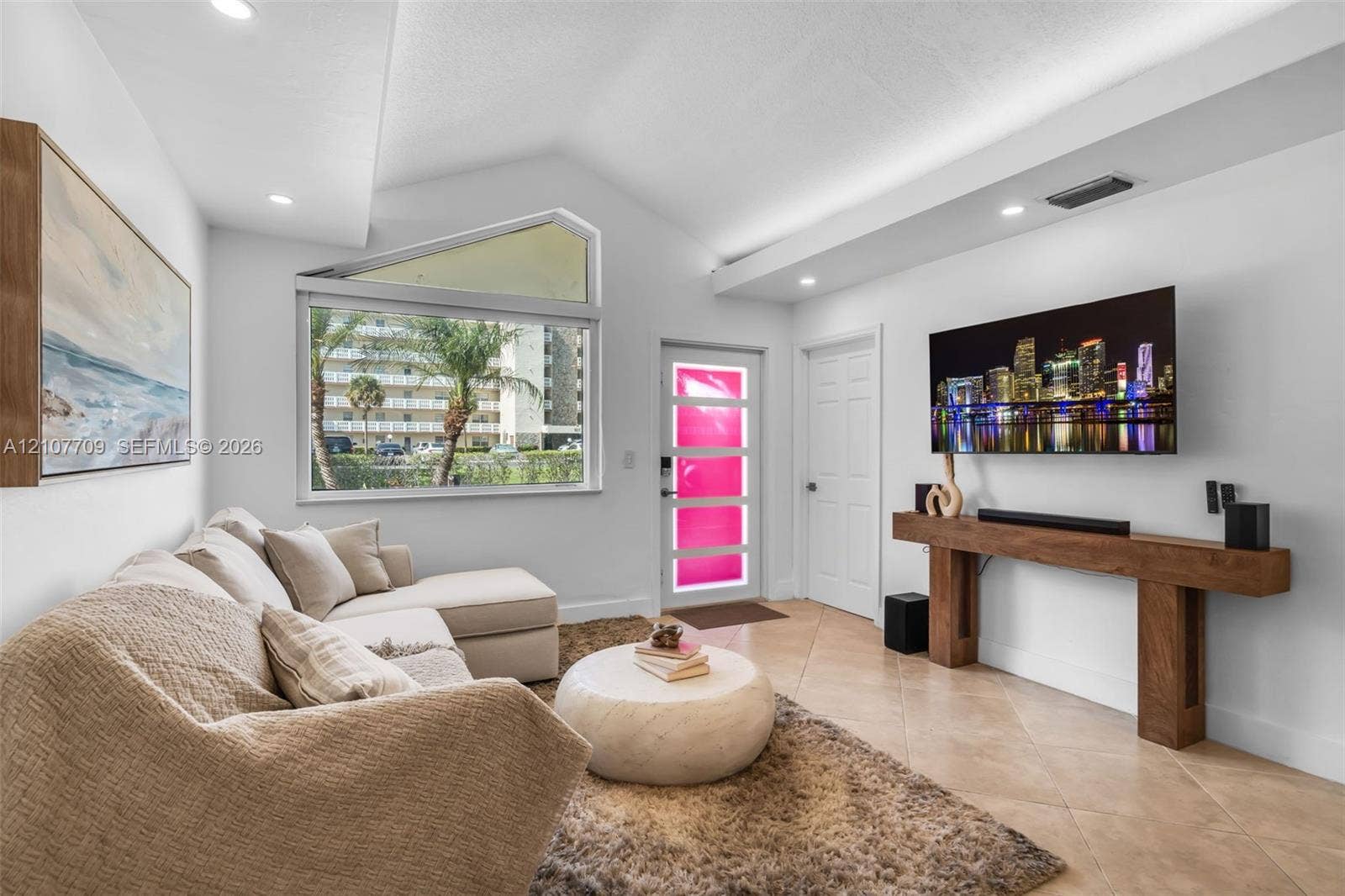 Vaulted ceiling, geometric transom window, tile flooring, and custom wall-mounted wood console