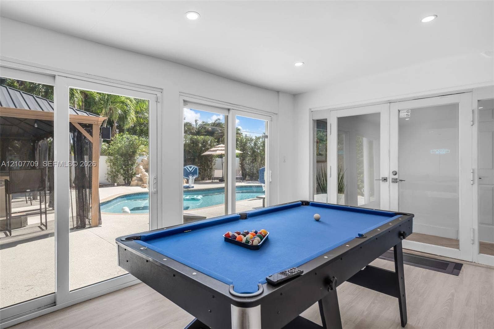 Bright interior space featuring recessed lighting, light-toned wood-finish flooring, full-height sliding glass doors, and glass-paned double doors