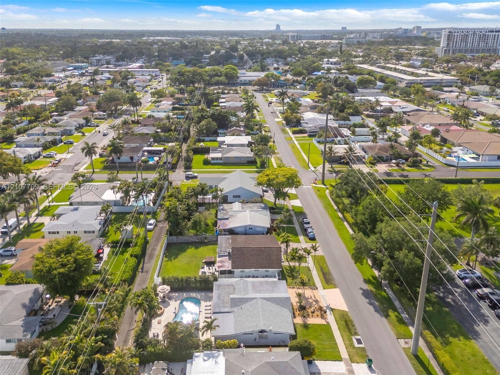 Aerial perspective featuring established residential streets, manicured landscaping, mature trees, and private in-ground swimming pools
