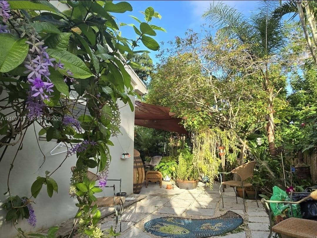 2321 N 57th Avenue, Hollywood, FL 33021 Landscaped outdoor area featuring stone paver flooring, established trees, flowering vines, and a textile shade canopy