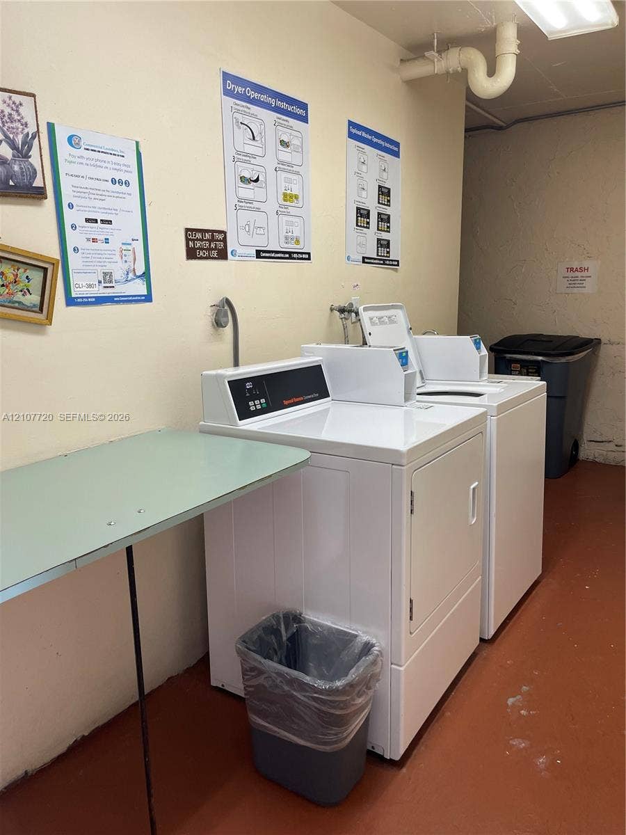 8921 S Hollybrook Boulevard, #204, Pembroke Pines, FL 33025 Laundry area featuring high-capacity white top-load washer and front-load dryer units with a built-in folding counter