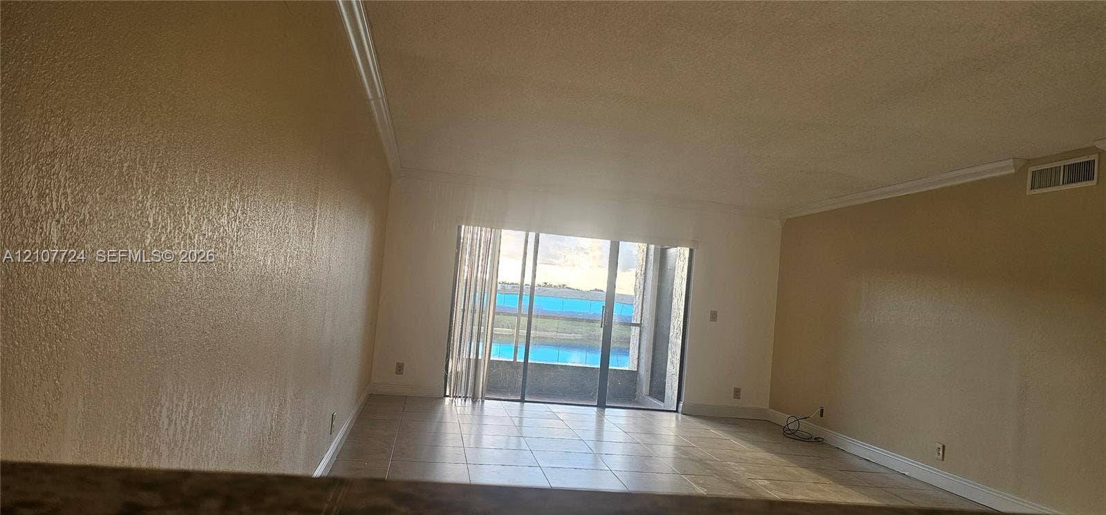 280 Racquet Club Road, #103, Weston, Weston, FL 33326 Living area featuring tile flooring, crown molding, and sliding glass doors opening to a balcony with water scenery