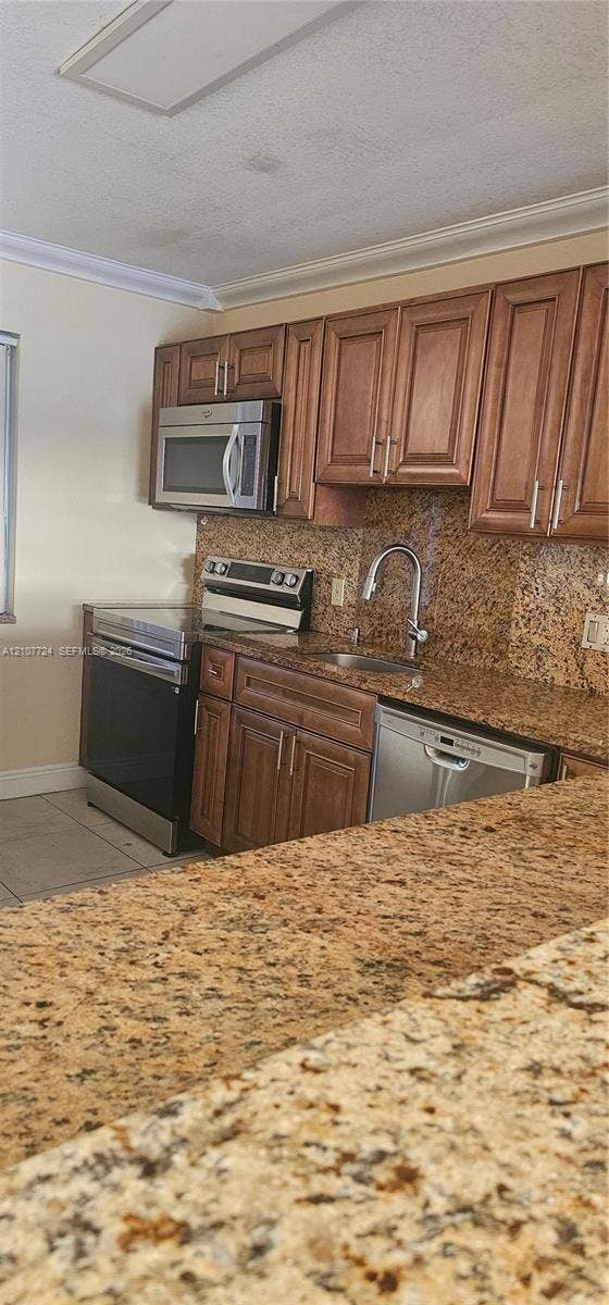 280 Racquet Club Road, #103, Weston, Weston, FL 33326 Kitchen featuring raised-panel wood cabinetry, natural stone countertops, stainless steel appliances, and an undermount sink with a gooseneck faucet