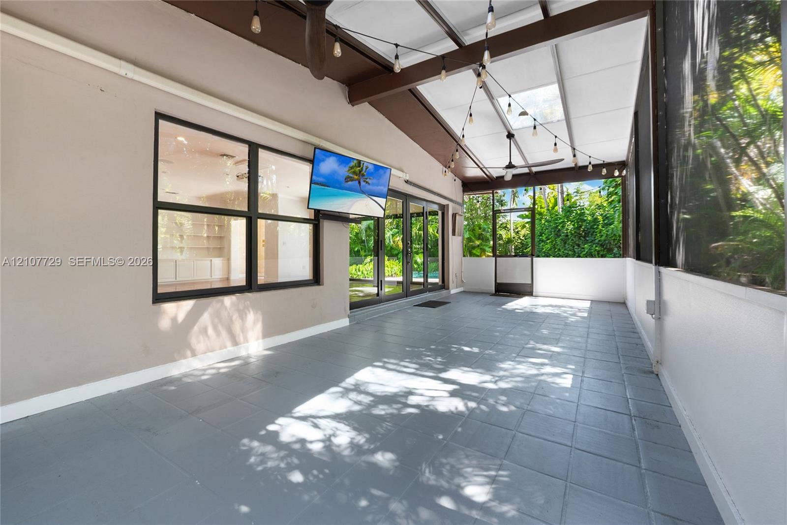 Screened patio featuring tile flooring, a skylight, exposed wood-beam ceiling, and sliding glass doors